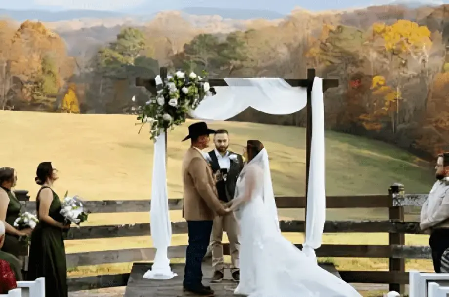 Outdoor wedding ceremony in scenic countryside setting.