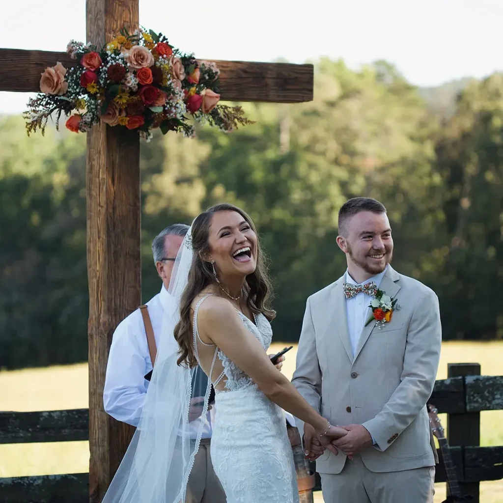 Bride and groom smiling during outdoor ceremony.